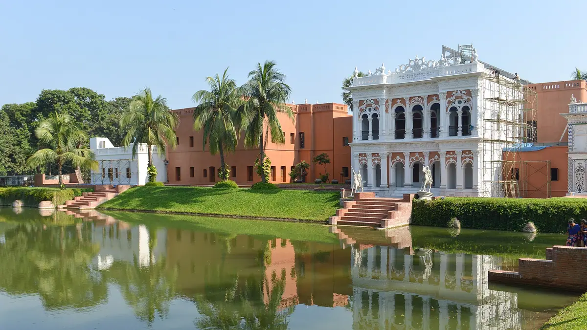 The white facade of the Folk Arts and Crafts Museum in Sonargaon, reflected in a pond